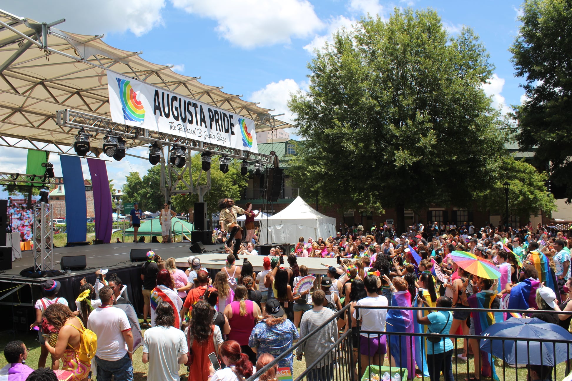 Background image of Augusta Pride stage surrounded by attendees